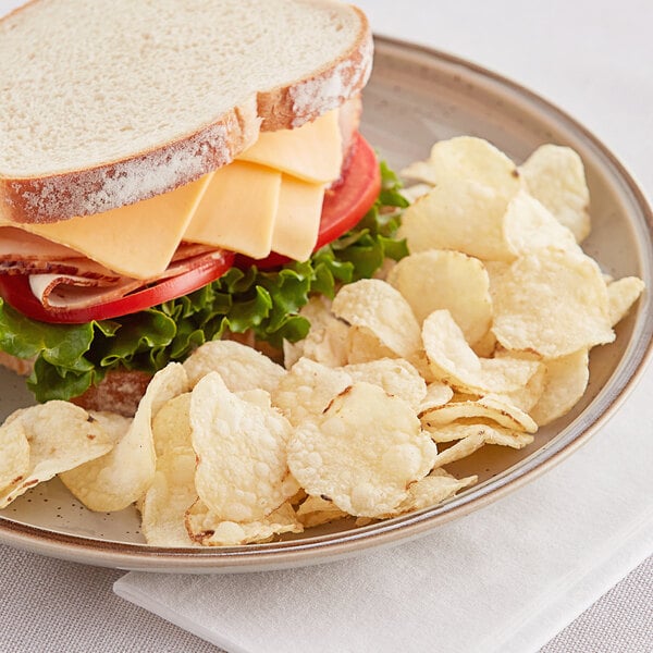 A plate with a sandwich, lettuce, tomato, bacon, cheese, and Martin's Kettle-Cook'd potato chips.