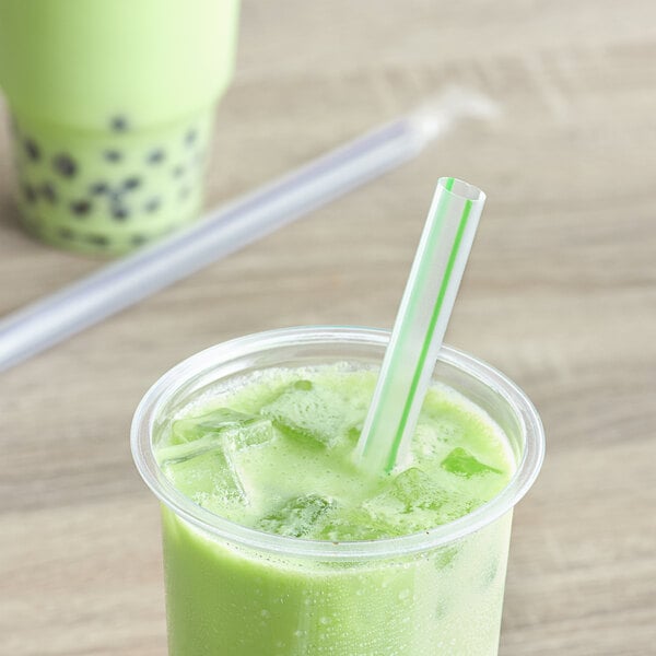 A green drink in a plastic cup with a Choice multicolor striped boba straw.
