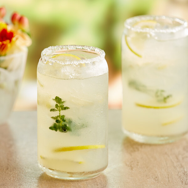 A glass of lemonade with ice, lemon, and mint next to a glass jar of ReaLemon lemon juice.