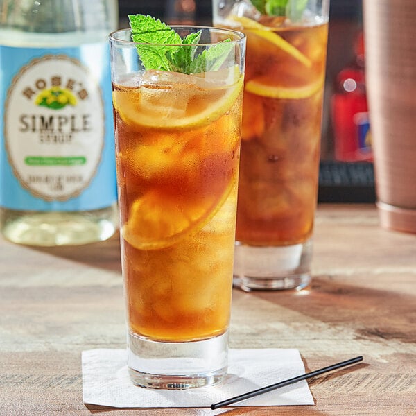 A glass of Rose's Simple Syrup iced tea with lemons and mint leaves.