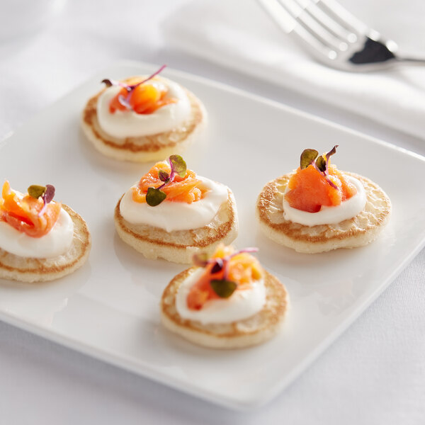 A close-up of a plate of Bemka Mini French Blinis with cream cheese and salmon toppings.