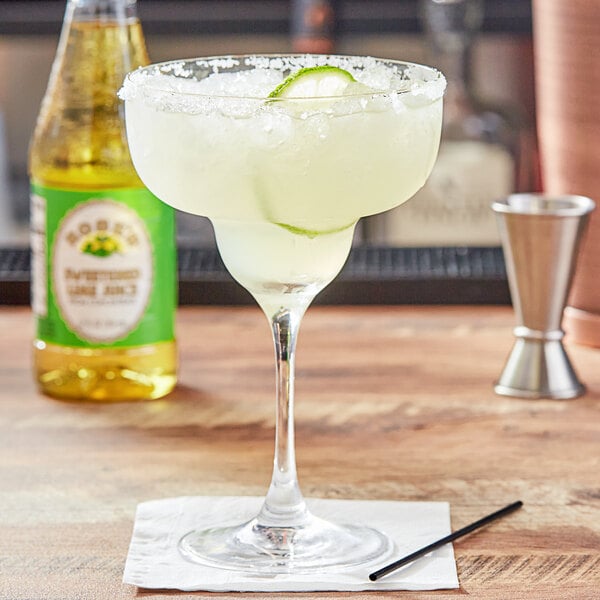 A margarita glass with a drink made with Rose's Sweetened Lime Juice on a napkin.