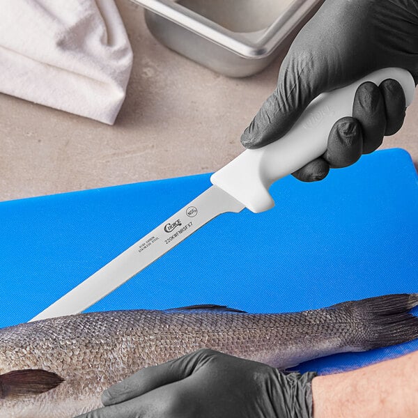 A person using a Choice 7" Narrow Semi-Flexible Fillet Knife to cut a fish.