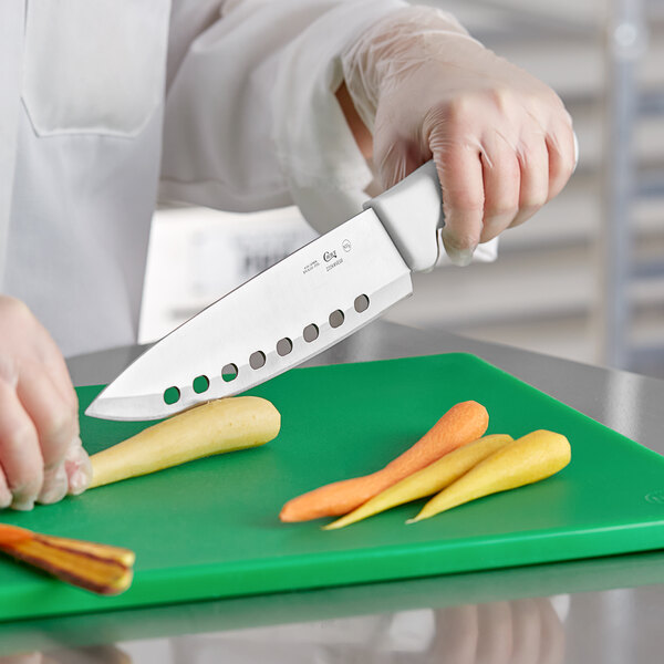 A person cutting carrots on a cutting board with a Choice 8" vegetable knife.