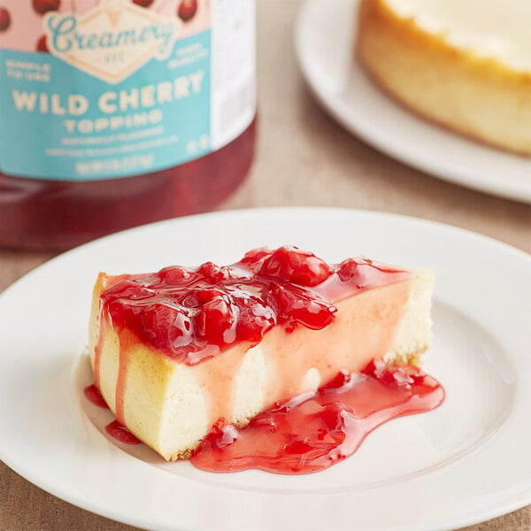 A slice of cheesecake with Creamery Ave. cherry topping on a white plate.