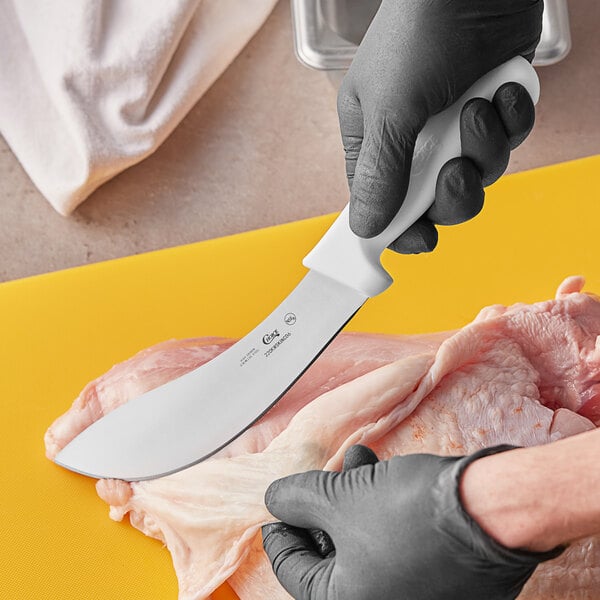 A person using a Choice curved skinning knife to cut meat.