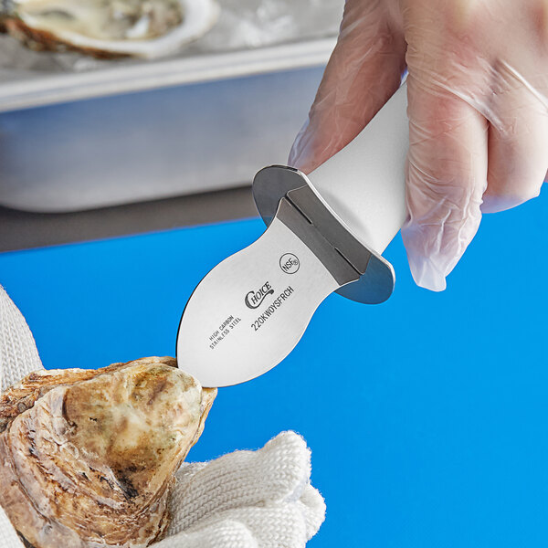 A person using a Choice Frenchman Style Oyster Knife with a white handle to cut an oyster.