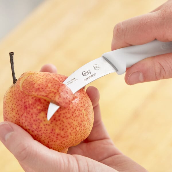 A person peeling a pear with a Choice Bird's Beak Paring Knife with a white handle.