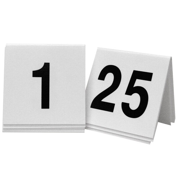 Two white Cal-Mil table tents with black numbers on them.