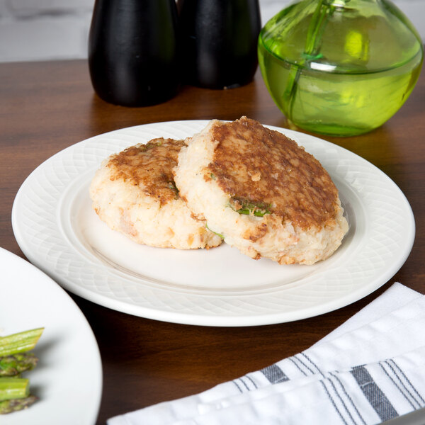 A Homer Laughlin Kensington Ameriwhite bright white china plate with two crab cakes and asparagus on it.