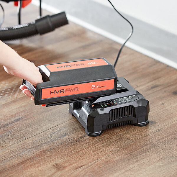 A person using a Hoover HVRPWR battery charger to charge a black battery.