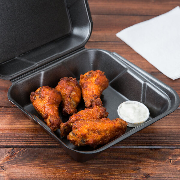 A black Genpak foam container with fried chicken and dipping sauce.