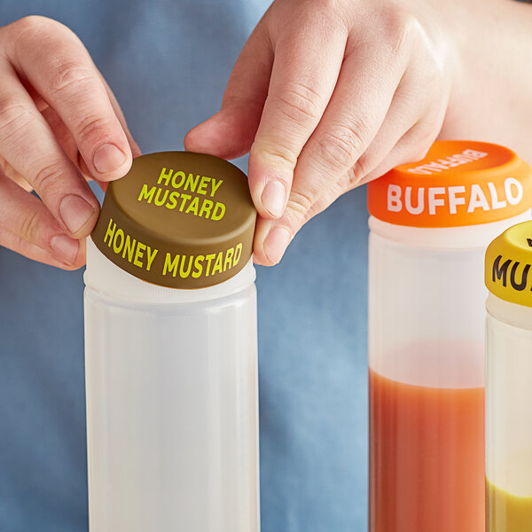 A person using a Choice Honey Mustard silicone lid on a squeeze bottle of mustard.