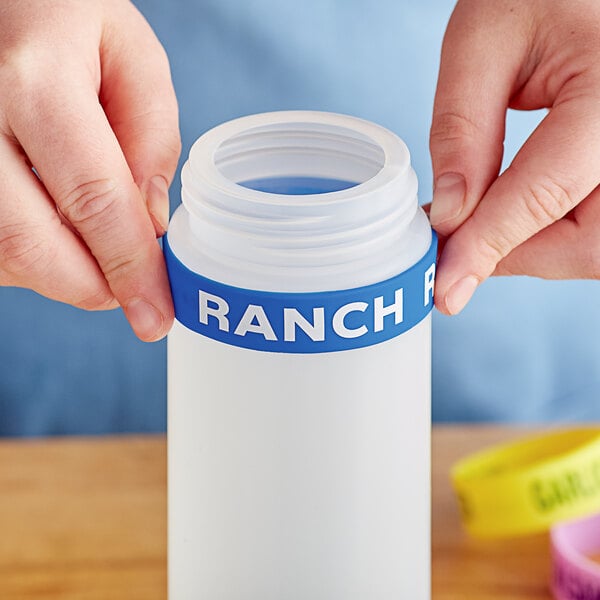 A person holding a "Ranch" silicone label band on a squeeze bottle.