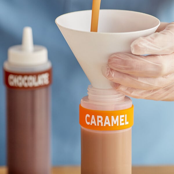 A person pouring caramel from a Choice silicone squeeze bottle into a container.