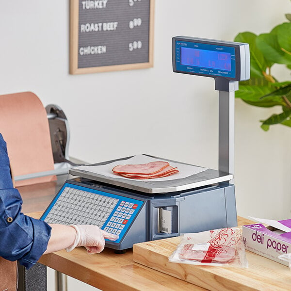 A person using the AvaWeigh PCSP60T scale to weigh meat on a counter in a deli.