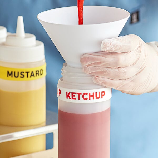 A hand pouring red liquid from a Choice Ketchup bottle with a label band into a container.