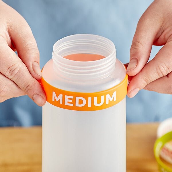 A person's hand holding a medium silicone label band on a plastic bottle.