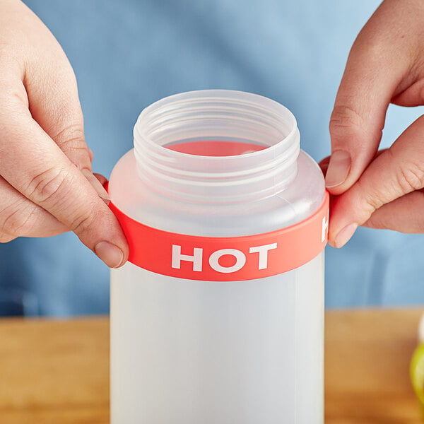 A person using a hot silicone label band on a plastic squeeze bottle.