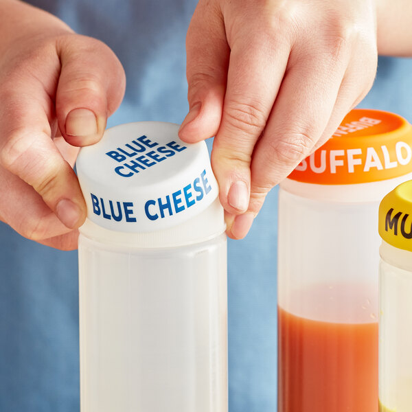 A person using a blue Choice silicone lid on a squeeze bottle of blue cheese.