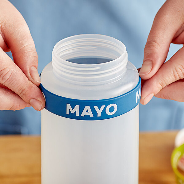 A person holding a plastic container with a silicone label band that says "Mayo"