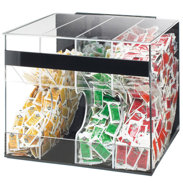 A clear plastic Cal-Mil top loading container with a variety of condiment packets inside.