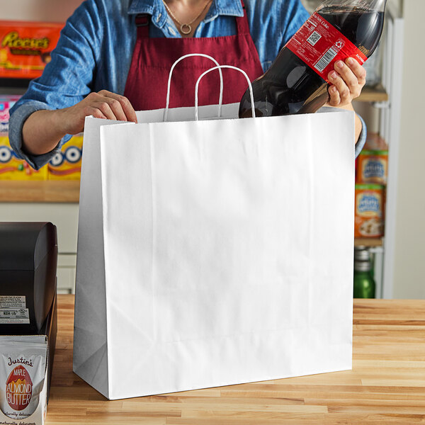 A woman holding a white Choice paper shopping bag with a bottle of soda inside.