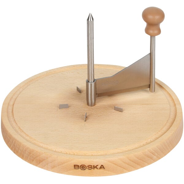 A Boska wood cheese curler with a knife and a wooden handle cutting cheese on a wooden cutting board.