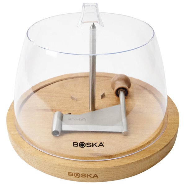 A Boska wood cheese curler with a clear plastic dome over a metal piece inside.