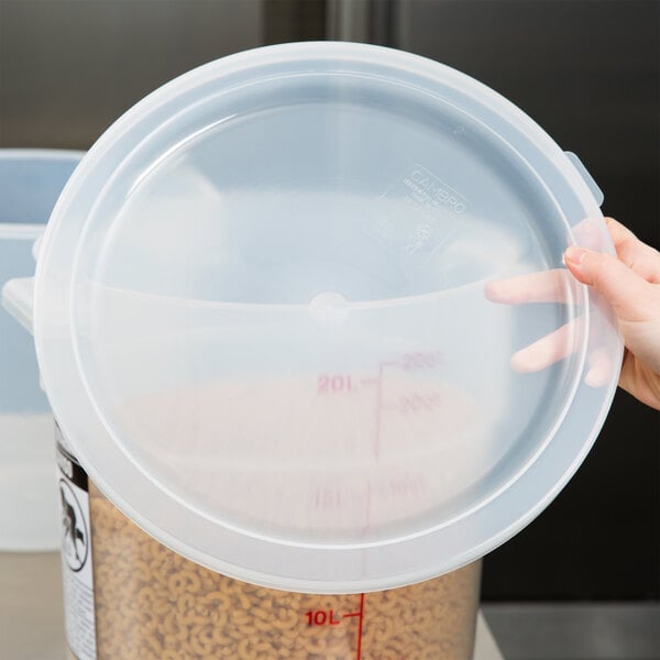A hand holding a Cambro translucent round polypropylene food storage container with food in it.
