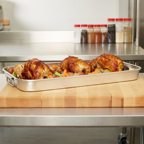 A Vollrath Wear-Ever aluminum roasting pan with cooked chicken and vegetables.