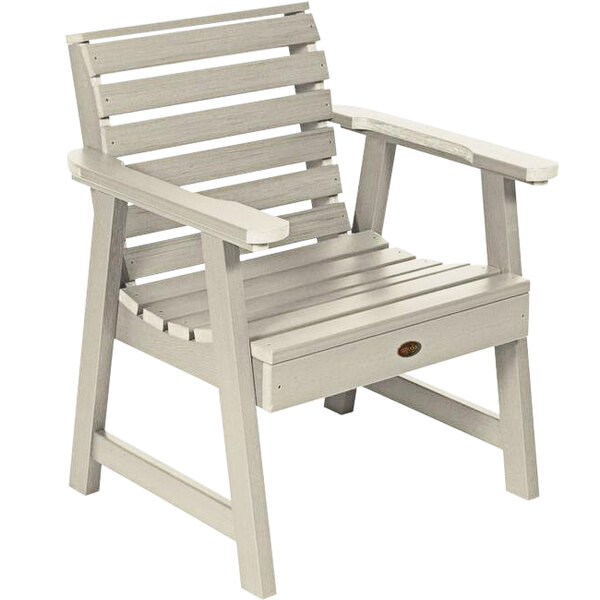 A white outdoor arm chair with a wooden seat.