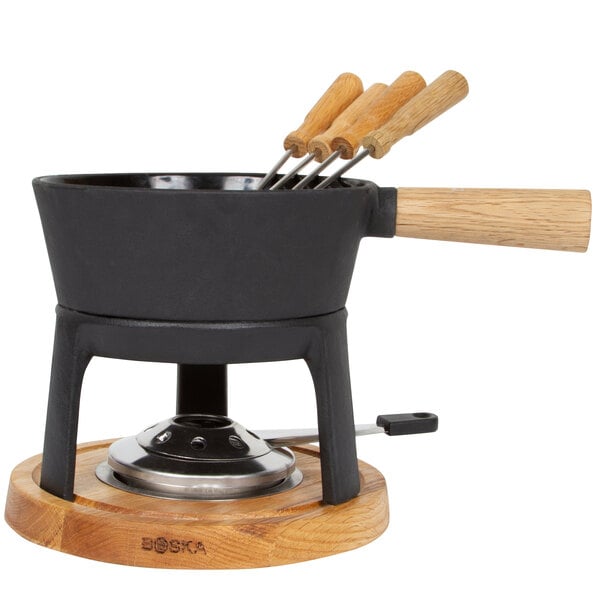 A Boska cast iron fondue pot set on a wooden stand with 6 forks.