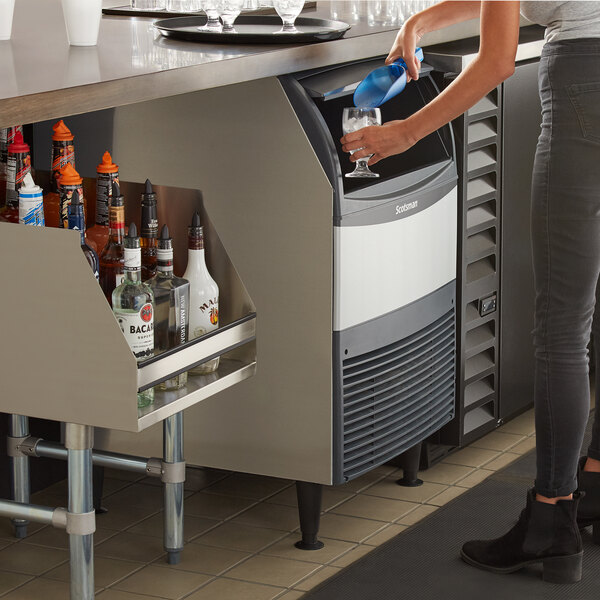 A person standing next to a Scotsman undercounter ice machine.
