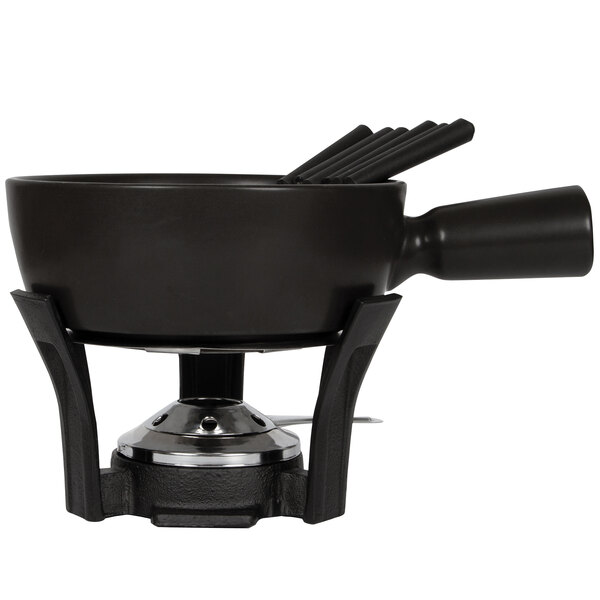 A black Boska ceramic fondue pot with 6 utensils on top.
