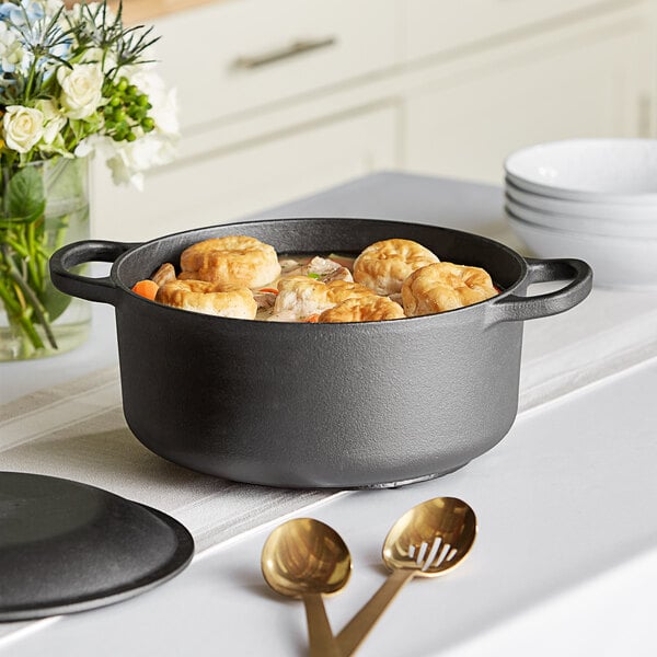 A Valor pre-seasoned cast iron Dutch oven filled with brown food on a table.