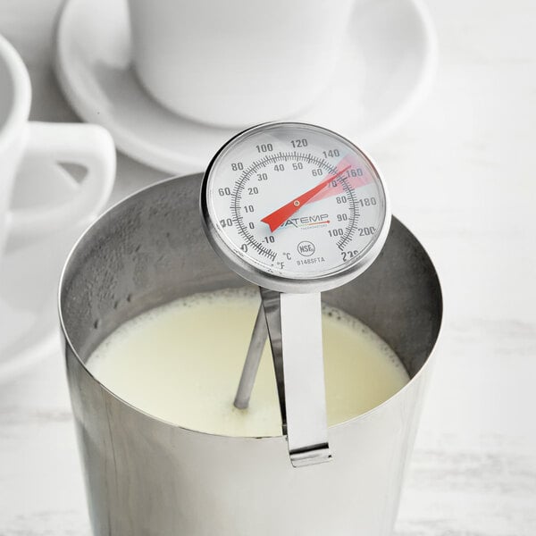 An AvaTemp frothing thermometer in a metal container with milk.