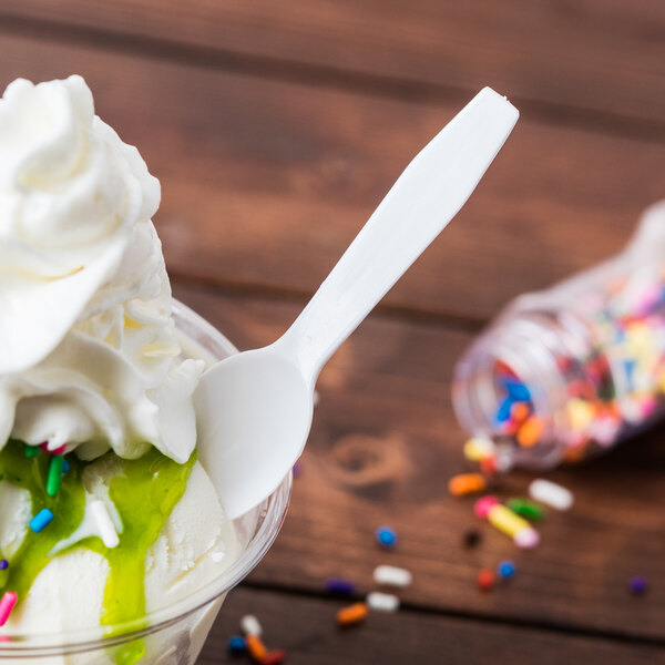 A white plastic Royal Paper taster spoon in a cup of ice cream.