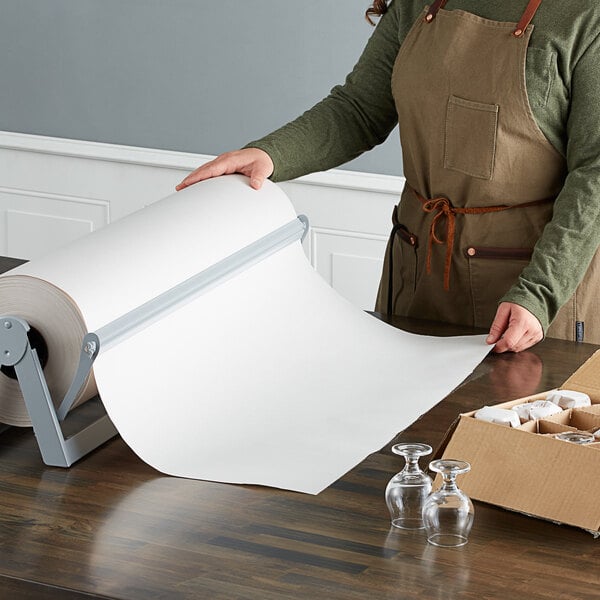 A woman wearing an apron holds a Lavex Newsprint packing paper roll.
