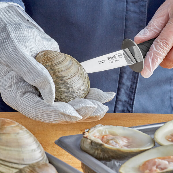 A person holding a Schraf clam knife over a tray of clams.