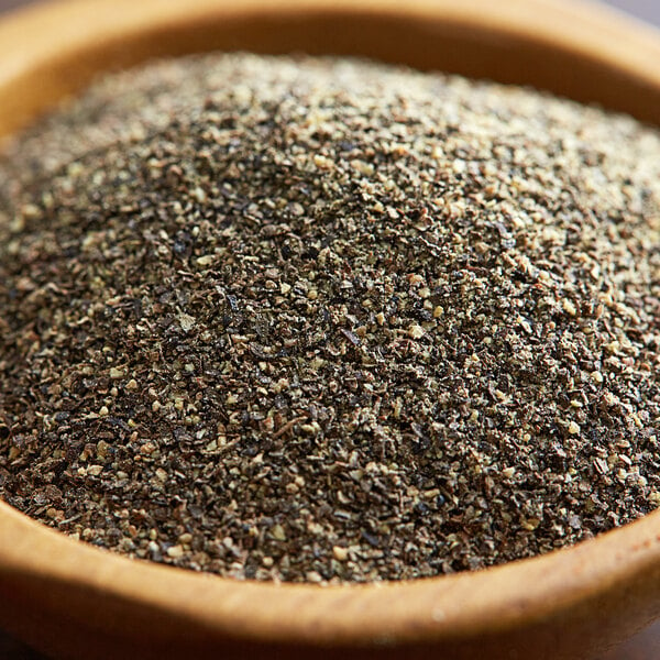A bowl of Regal Table Grind ground black pepper on a wooden table.