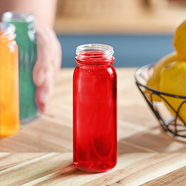 A 4 oz. clear PET round juice bottle with a red lid filled with red liquid.