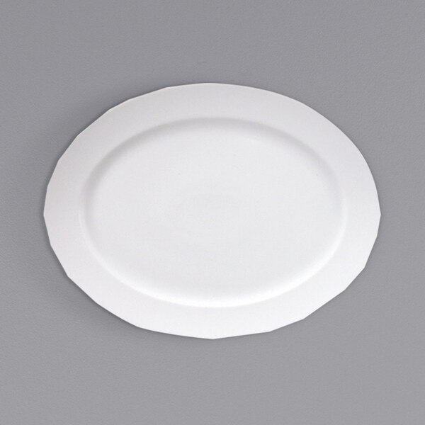 A Fortessa Ilona bright white china oval platter with a wide white rim on a gray surface.