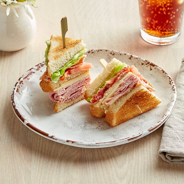A sandwich on a GET French Mill melamine plate with a drink on a table.