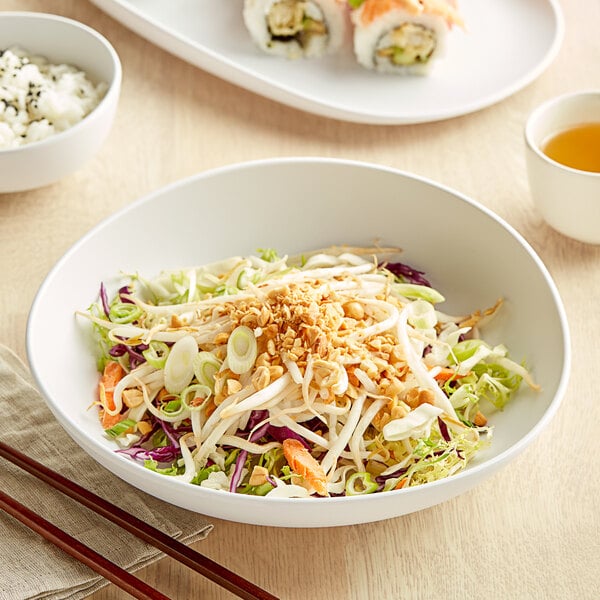 A white Riverstone melamine bowl filled with salad, vegetables, and nuts.