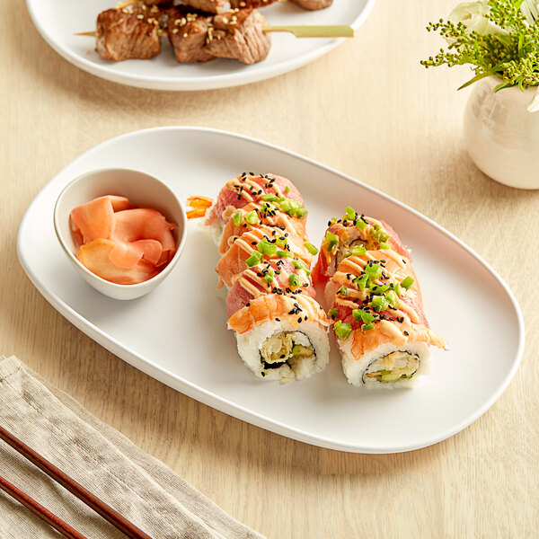 A white Riverstone melamine coupe plate with sushi, green onions, and black sesame seeds.