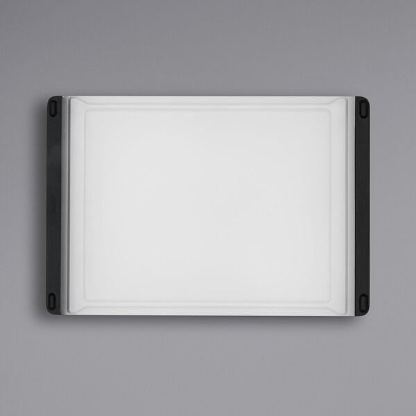 A white rectangular OXO polypropylene cutting board with black edges.