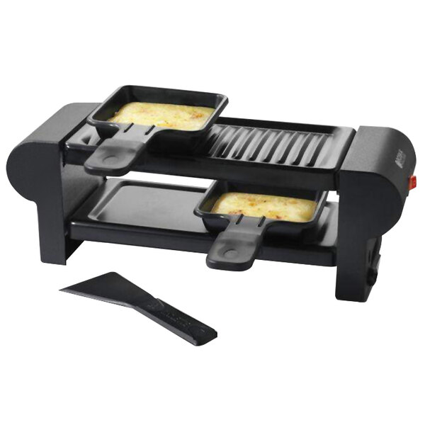 A black Boska electric raclette maker with two pans of food inside.