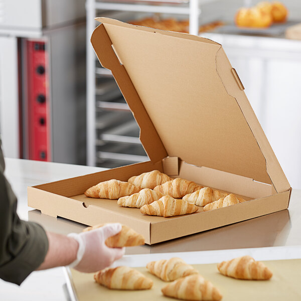 A person putting croissants in a Choice Kraft bakery box.