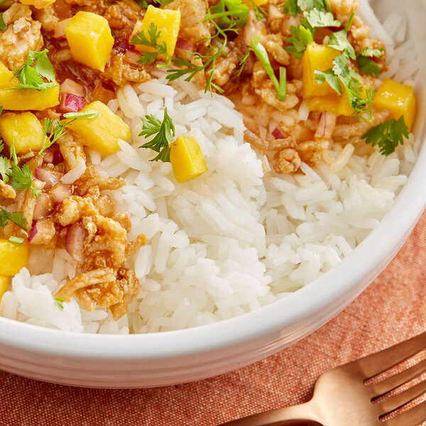 A bowl of Goya Thai white jasmine rice with meat and mangoes.